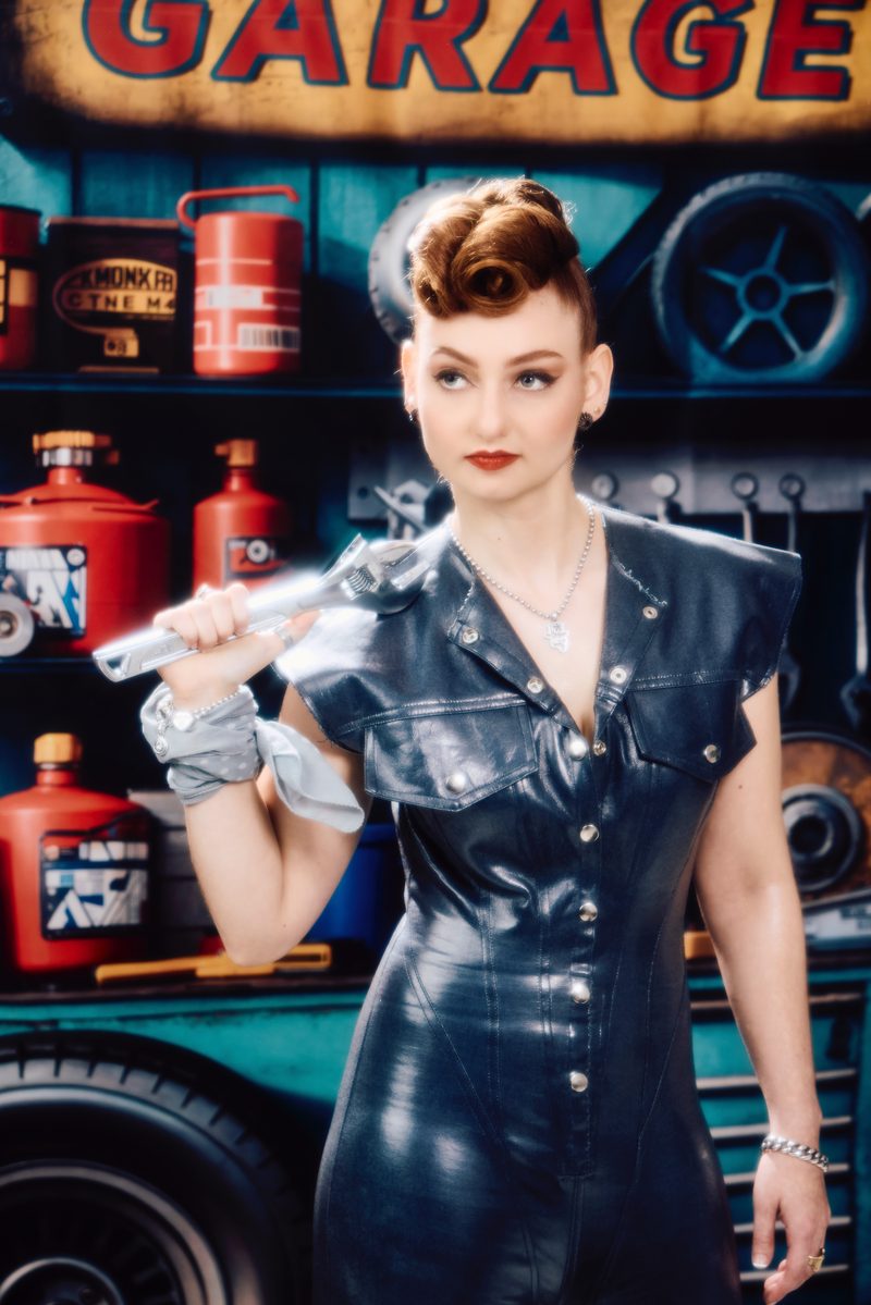Singer-songwriter Ashley Ann in a vintage garage set, holding a chrome wrench.